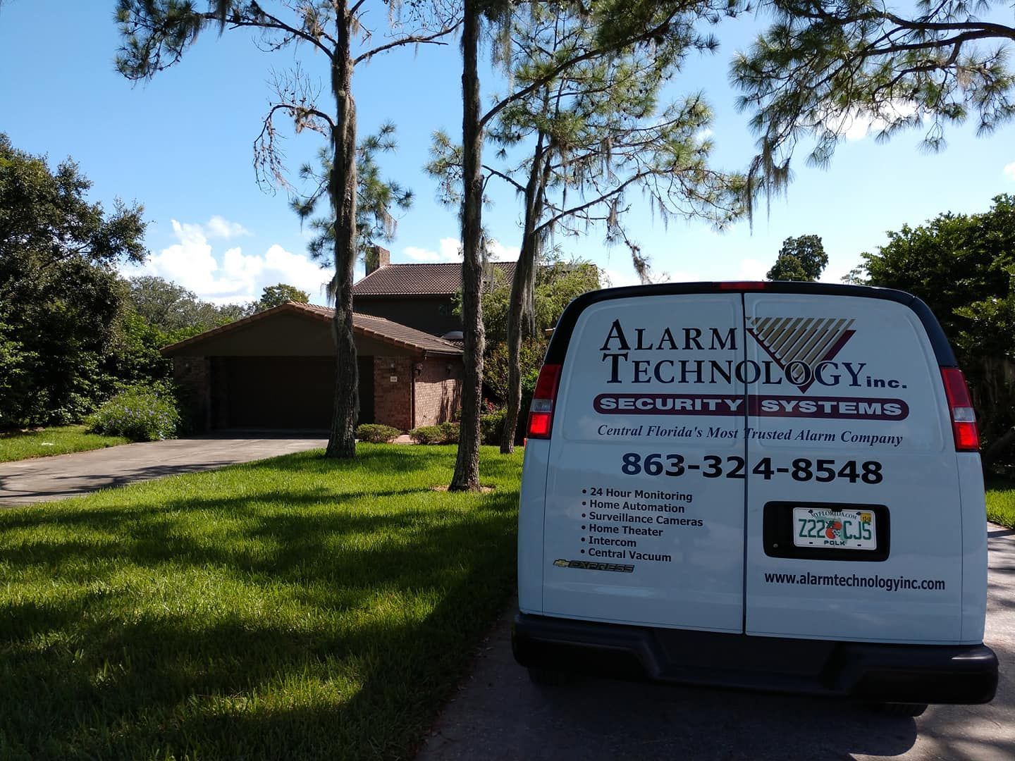 An alarm technology van is parked in front of a house