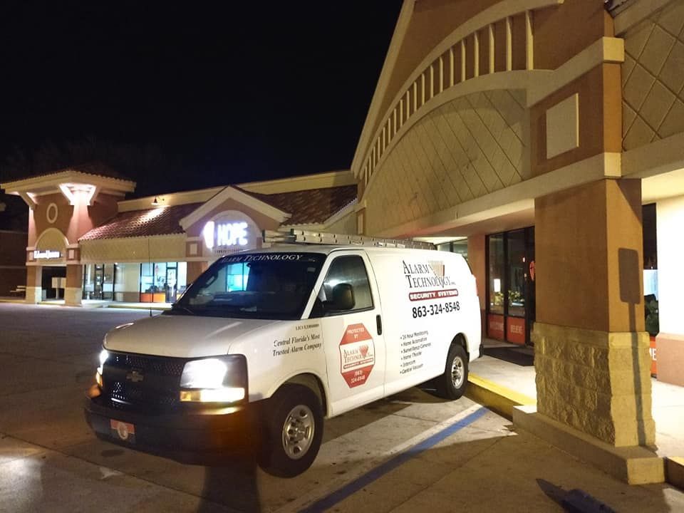 A white van is parked in front of a store at night