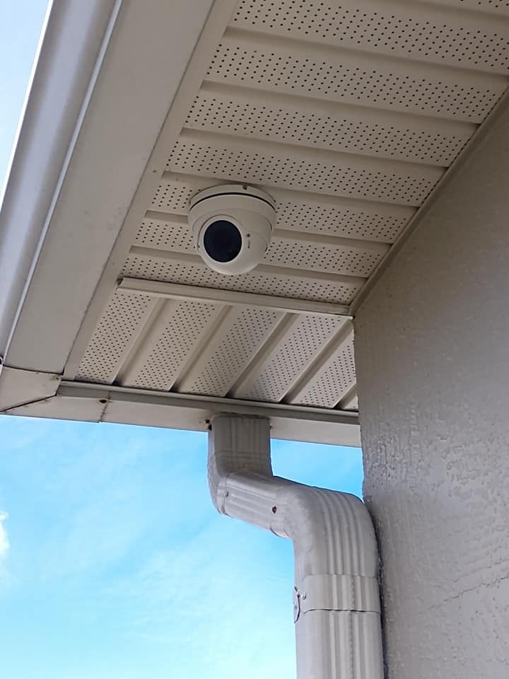 A security camera is mounted under the roof of a house.