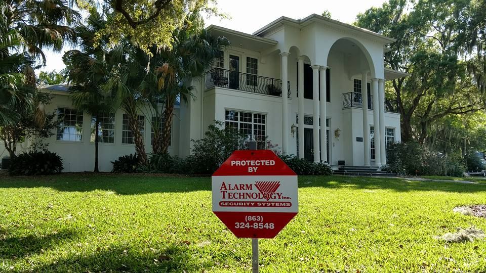 A large white house with a sign in front of it that says alarm technology