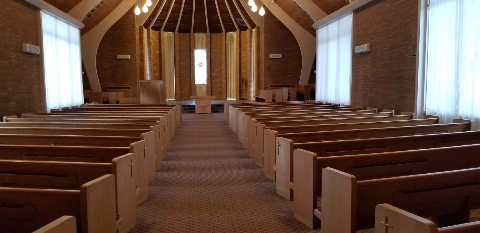 The inside of an empty church with rows of wooden benches.