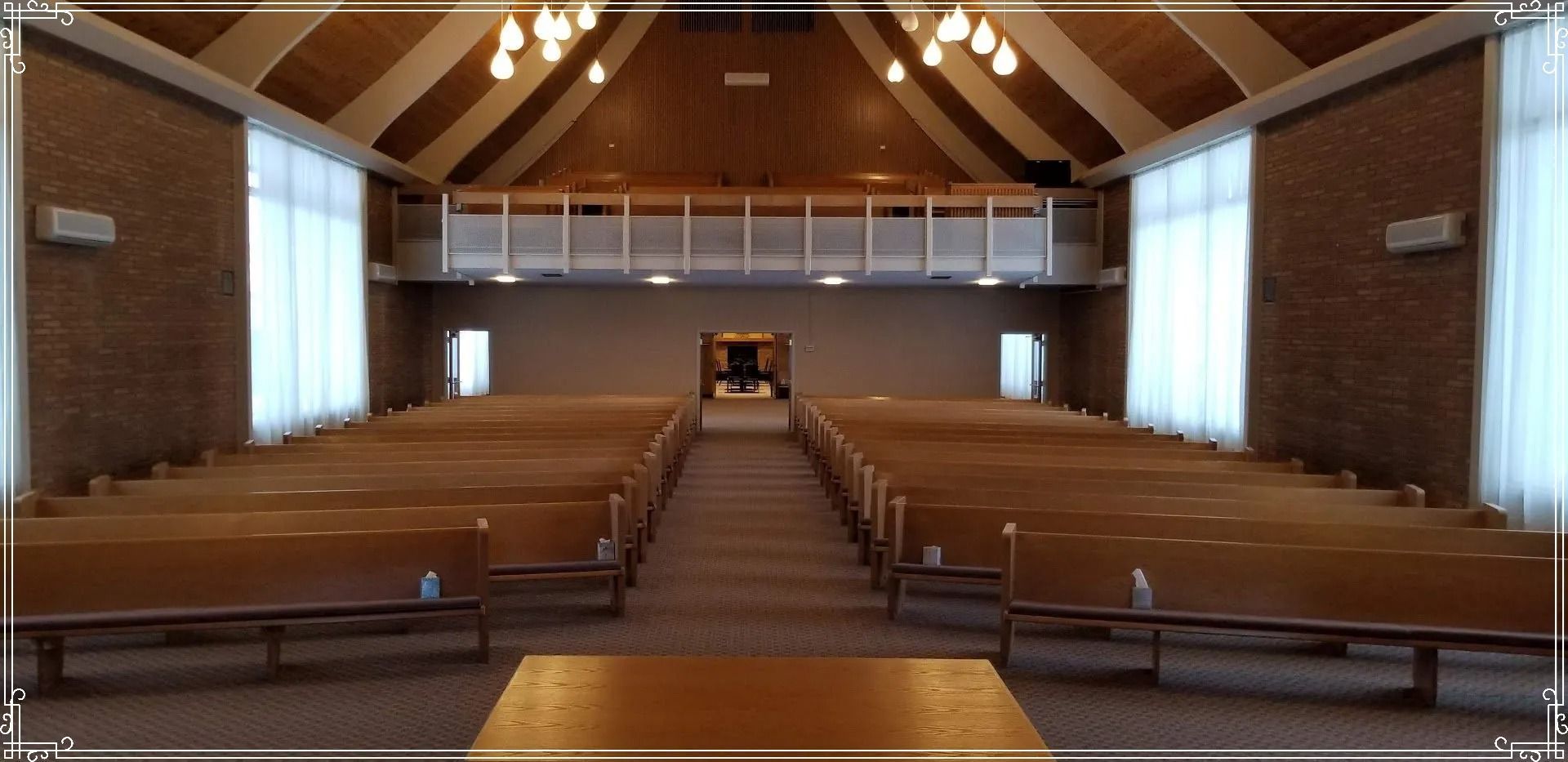 A church with rows of wooden benches and a balcony.