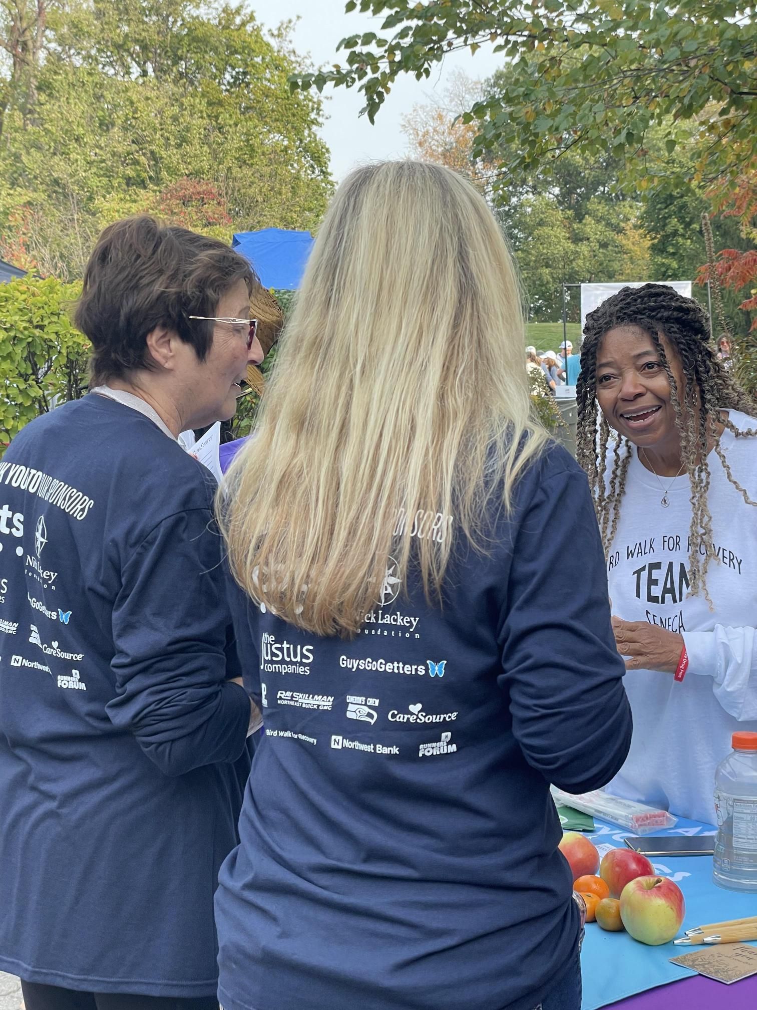 A group of women are standing around a table talking to each other.