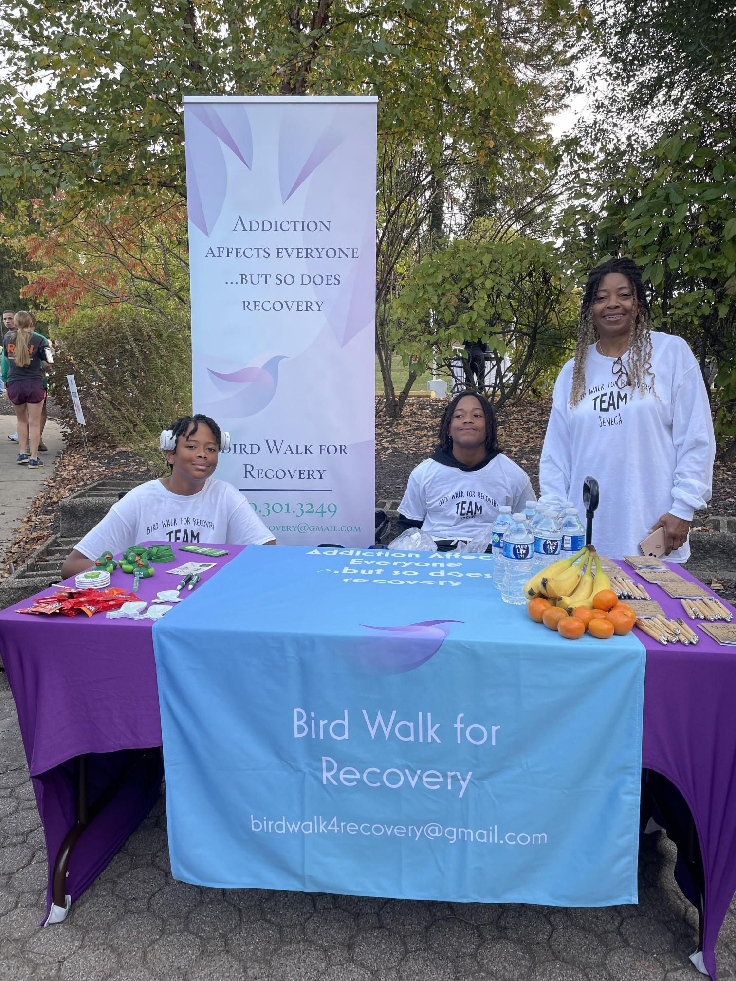 A group of people standing around a table with a sign that says bird walk for recovery.