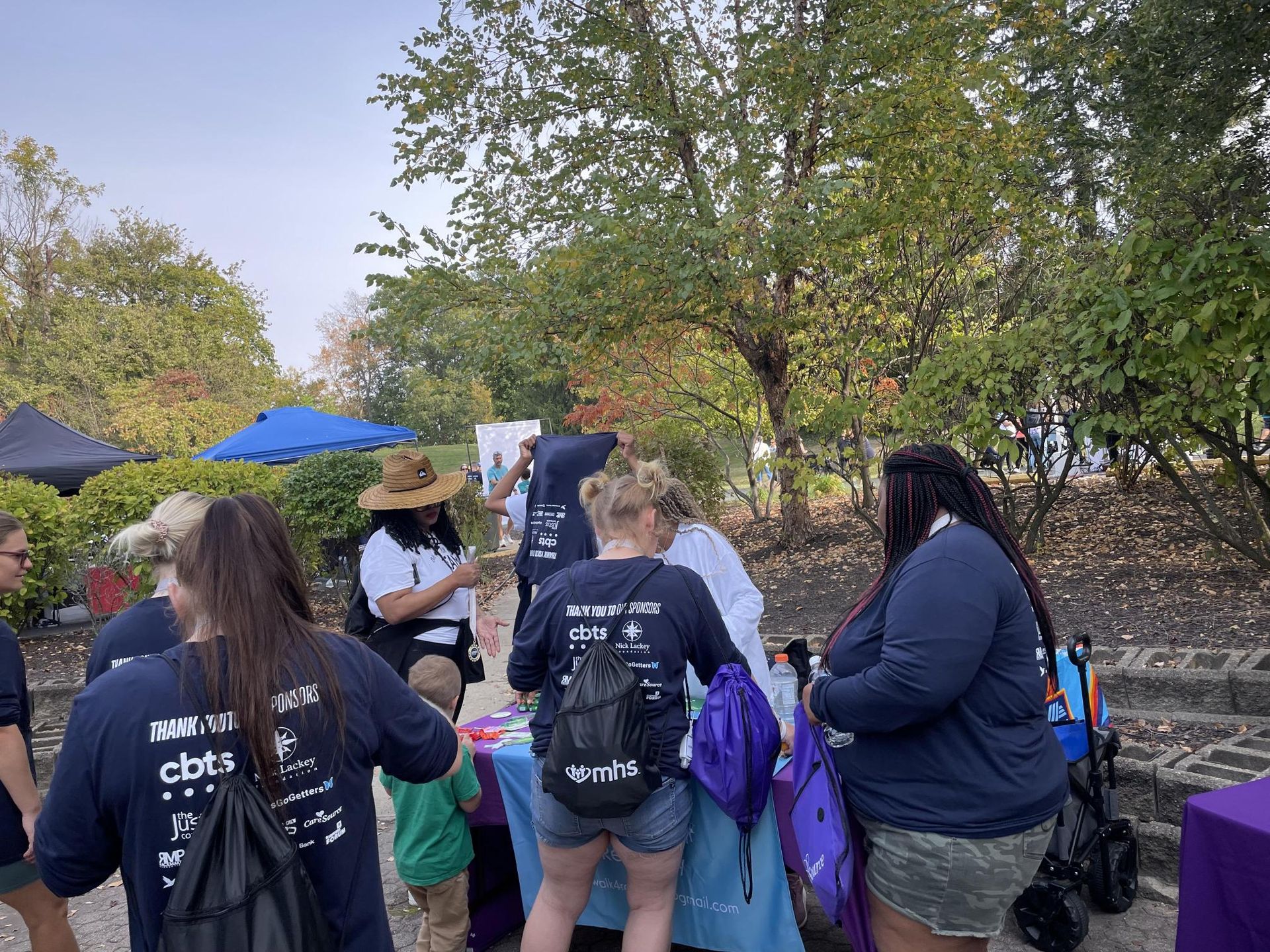 A group of people are standing around a table in a park.
