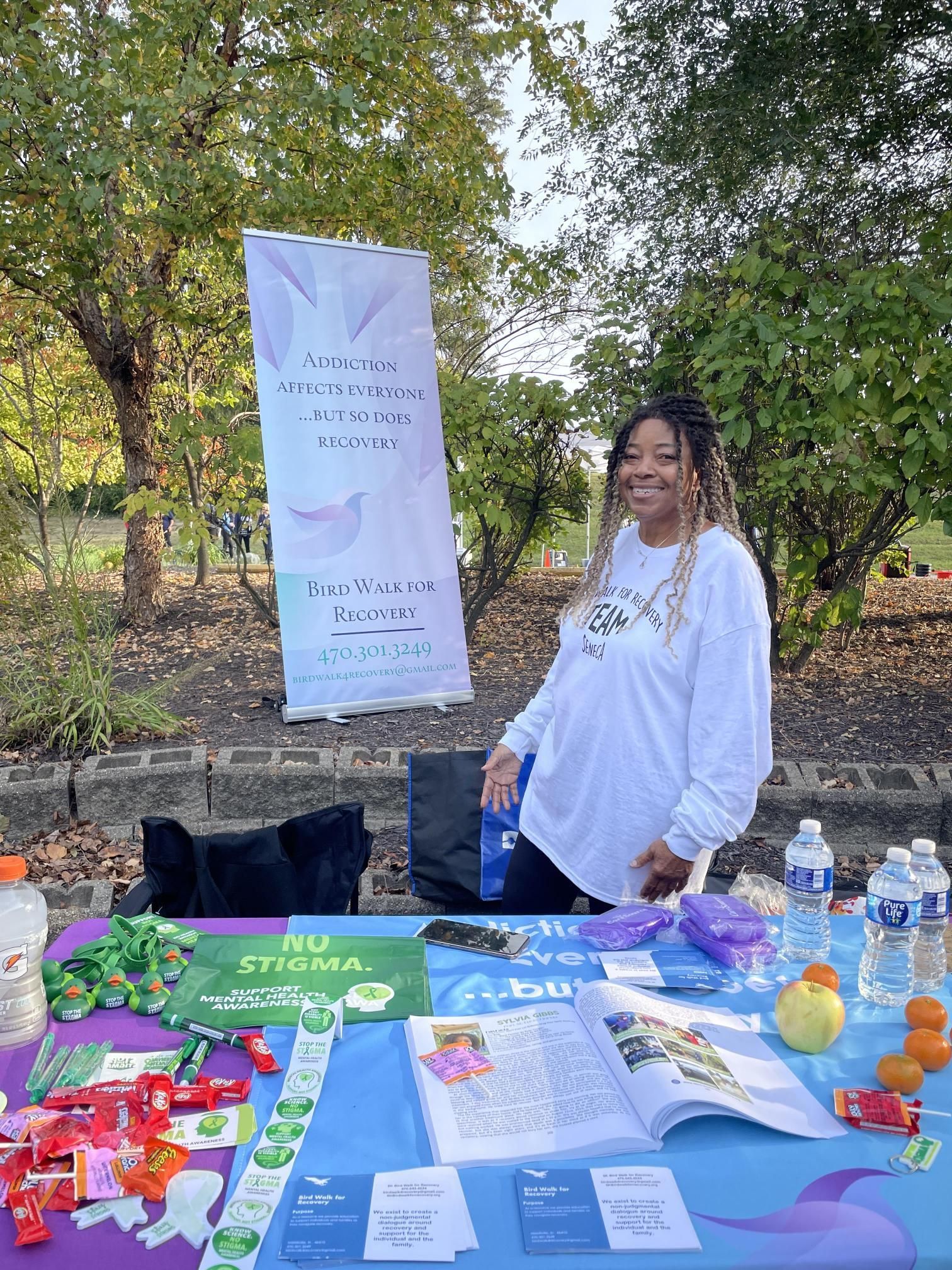 A woman is standing in front of a table with a sign on it.