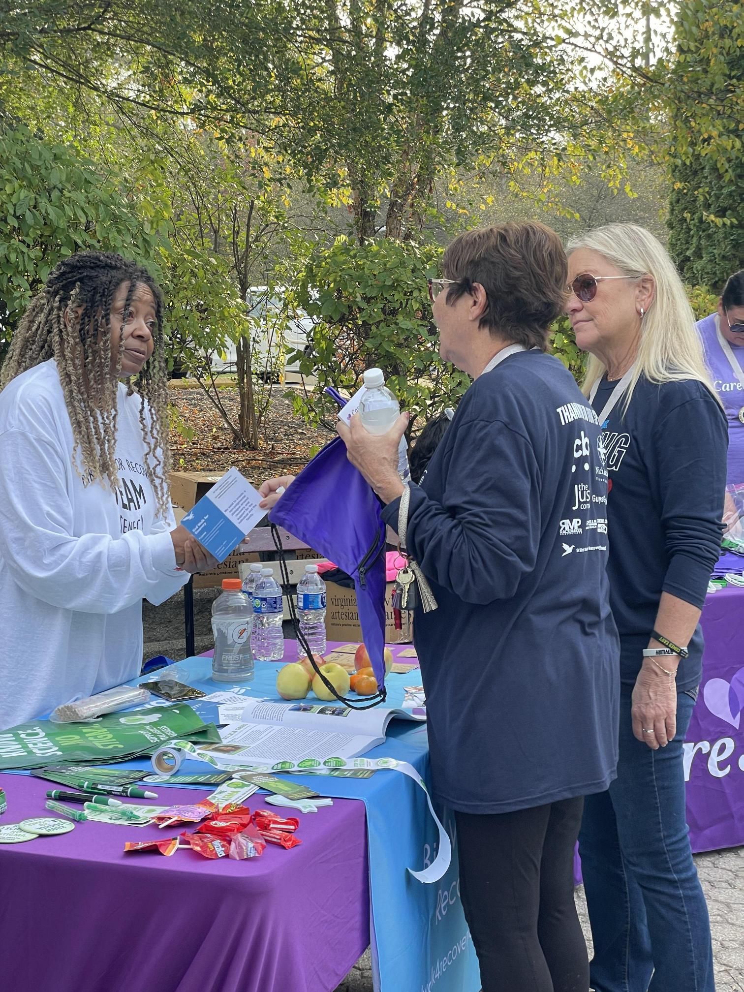 A group of women are standing around a table talking to each other.
