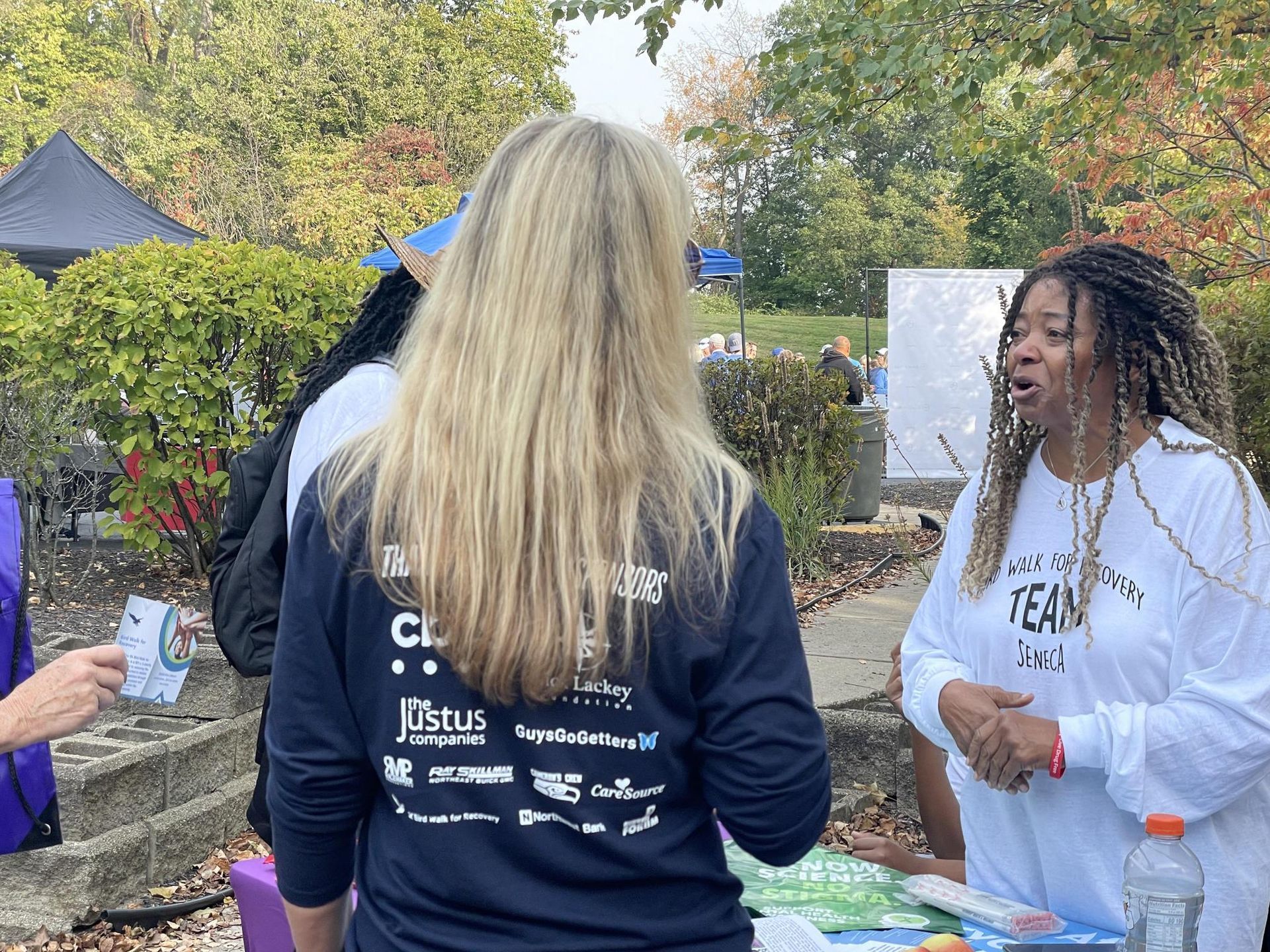 A group of women are standing around a table talking to each other.