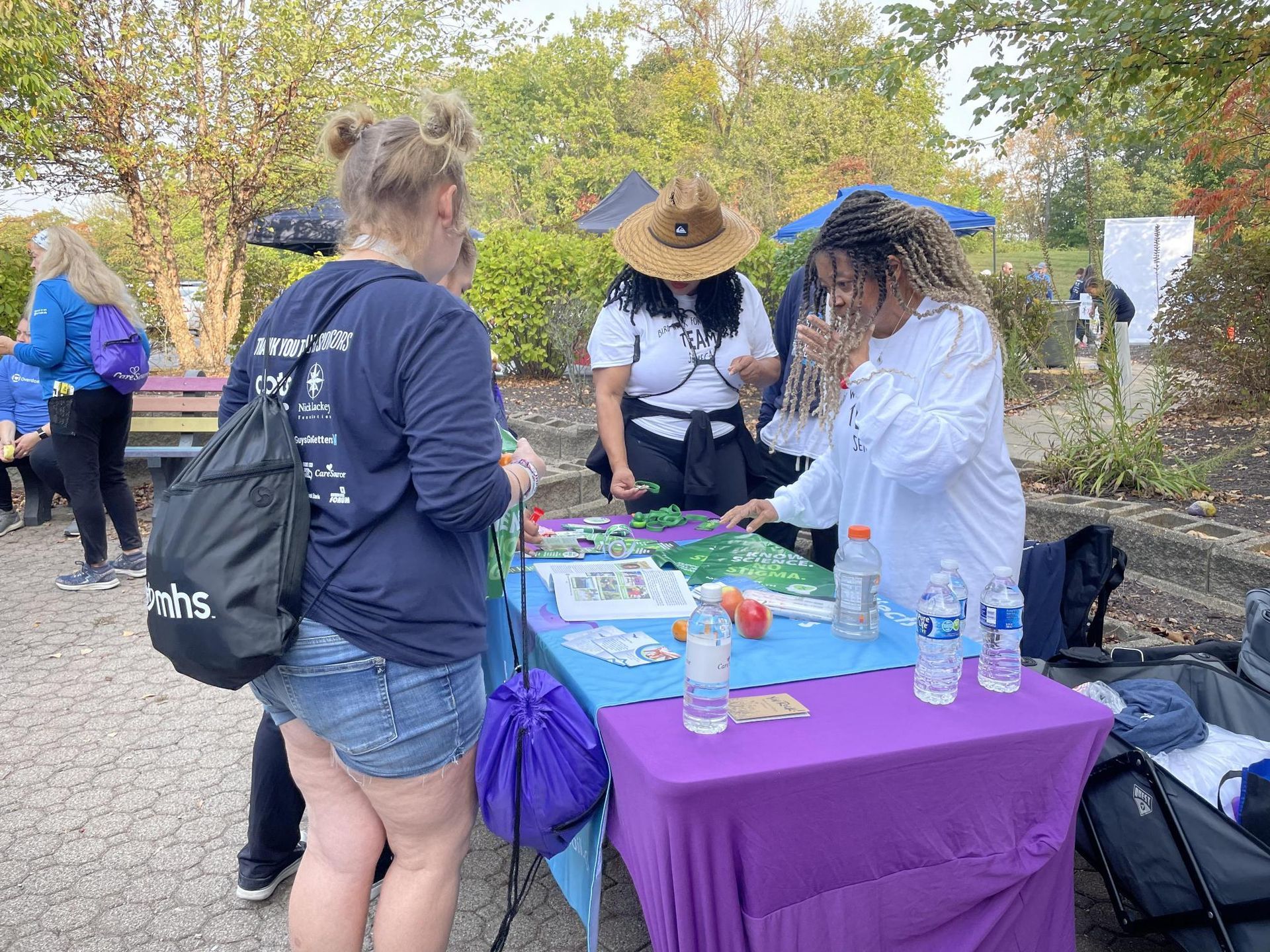 A group of women are standing around a table in a park.