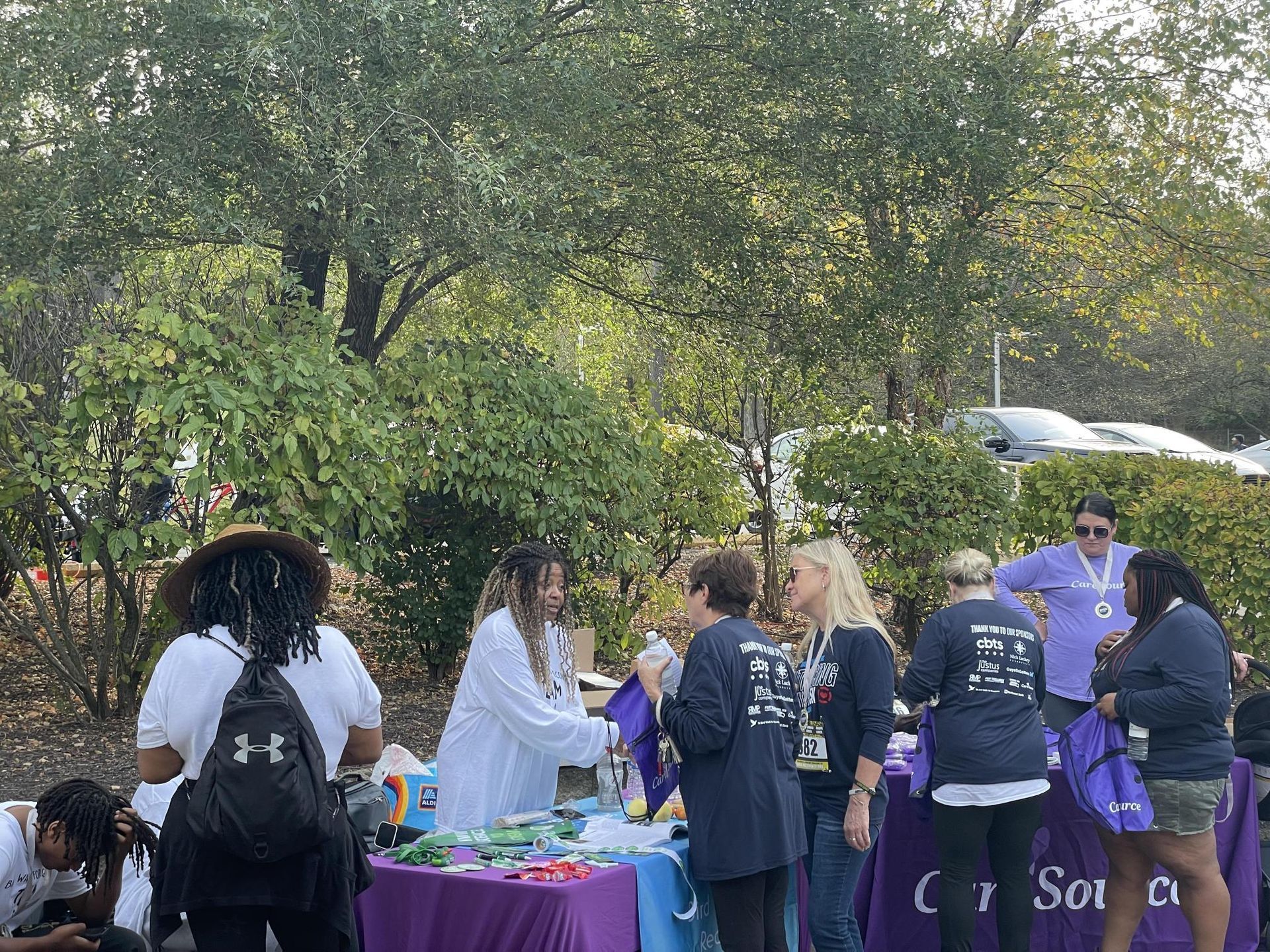 A group of people are standing around a table in a park.