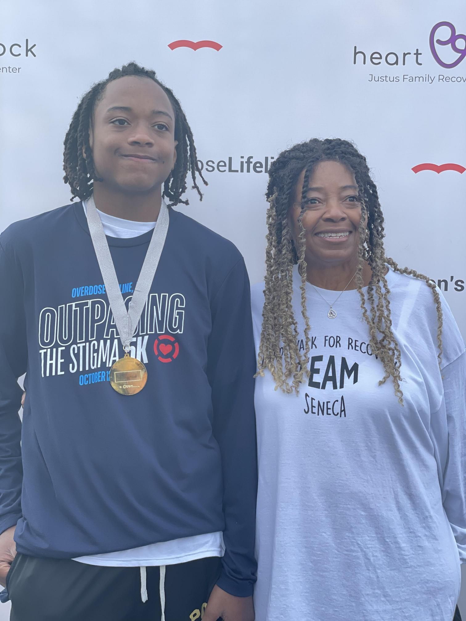 A man and a woman are posing for a picture . the man is wearing a medal around his neck.