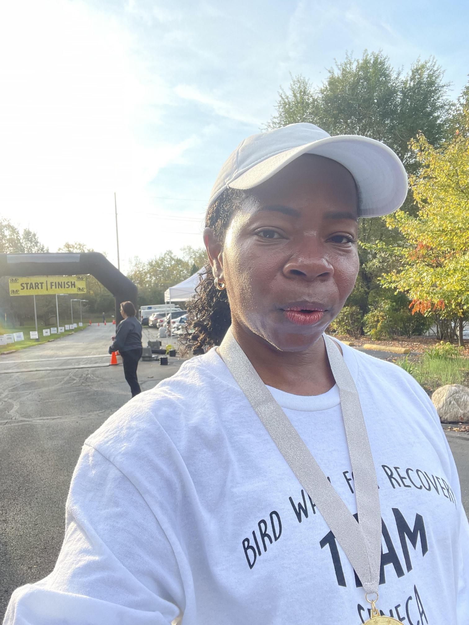 A woman wearing a hat and a medal is taking a selfie.