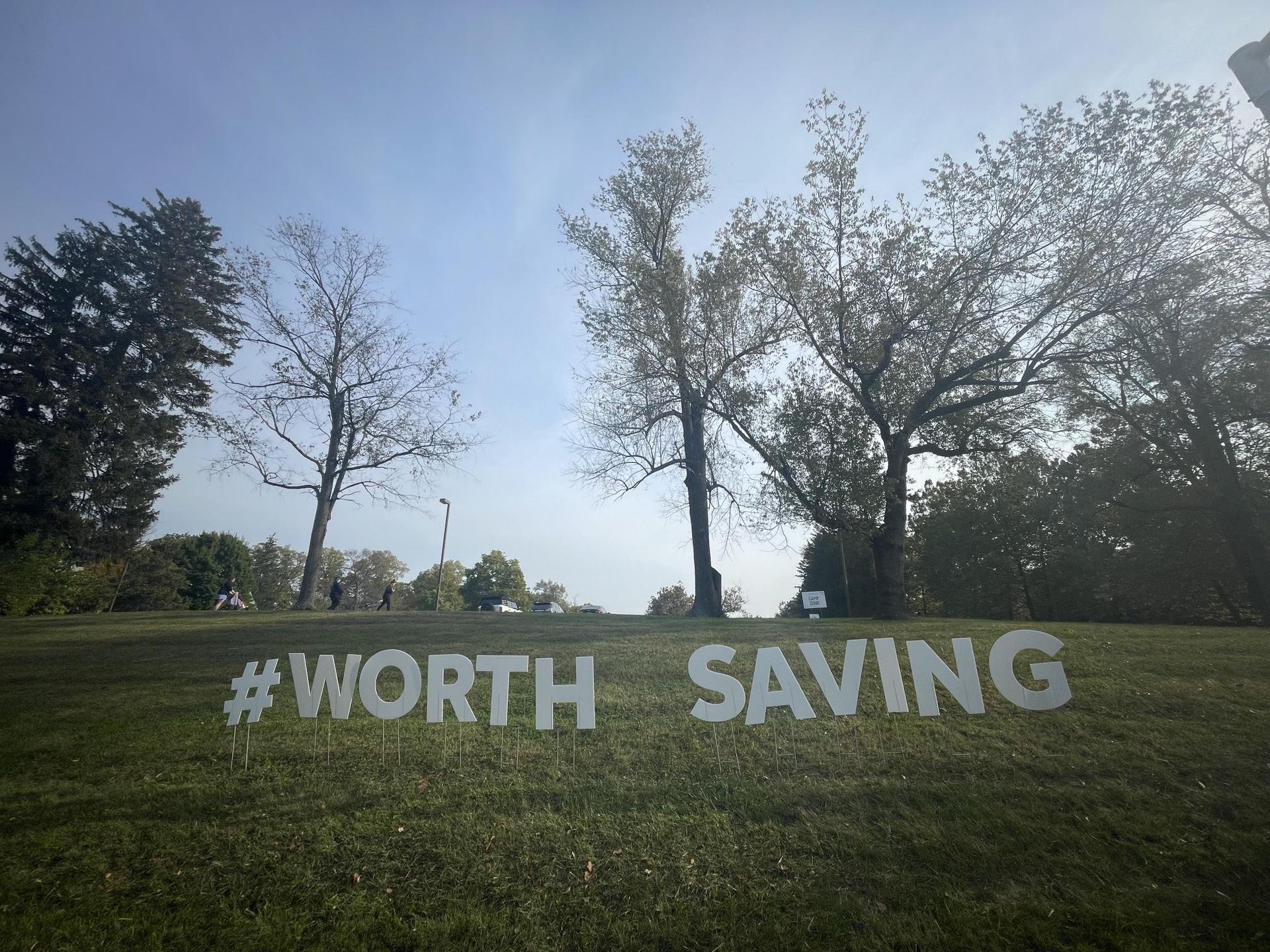 A sign in the grass that says #worth saving