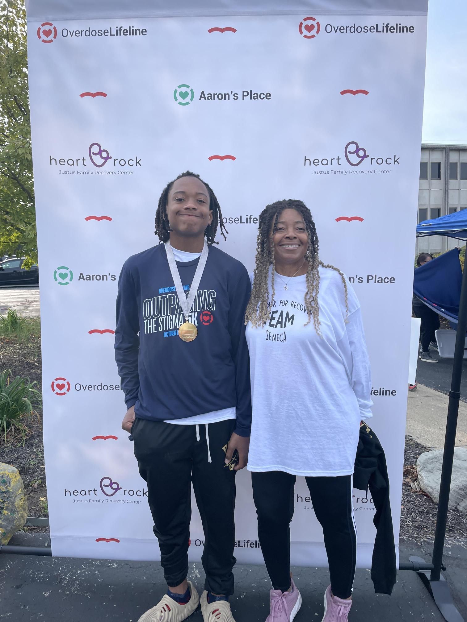 A man and a woman are standing next to each other in front of a wall.
