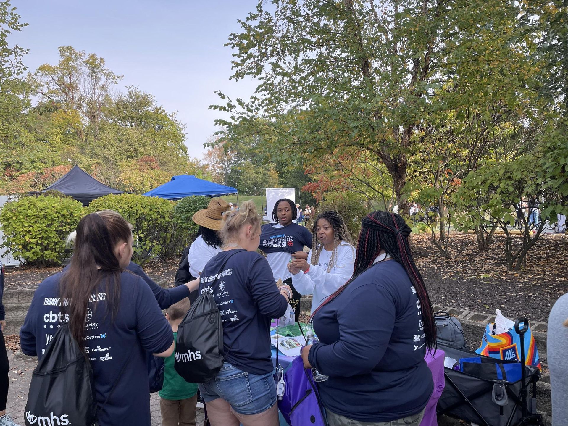 A group of women are standing around a table in a park.