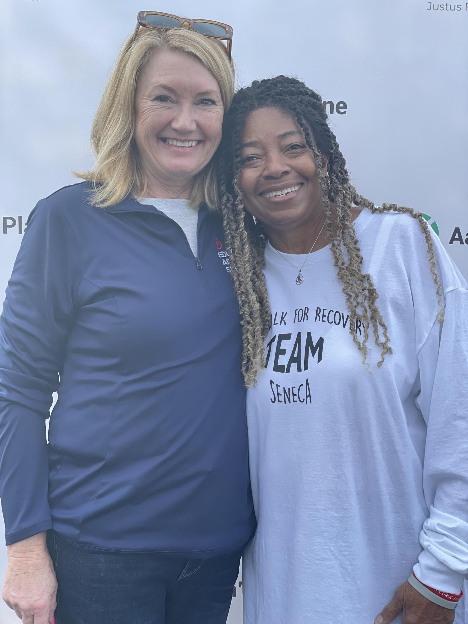 Two women are posing for a picture together and one of them is wearing a team shirt.