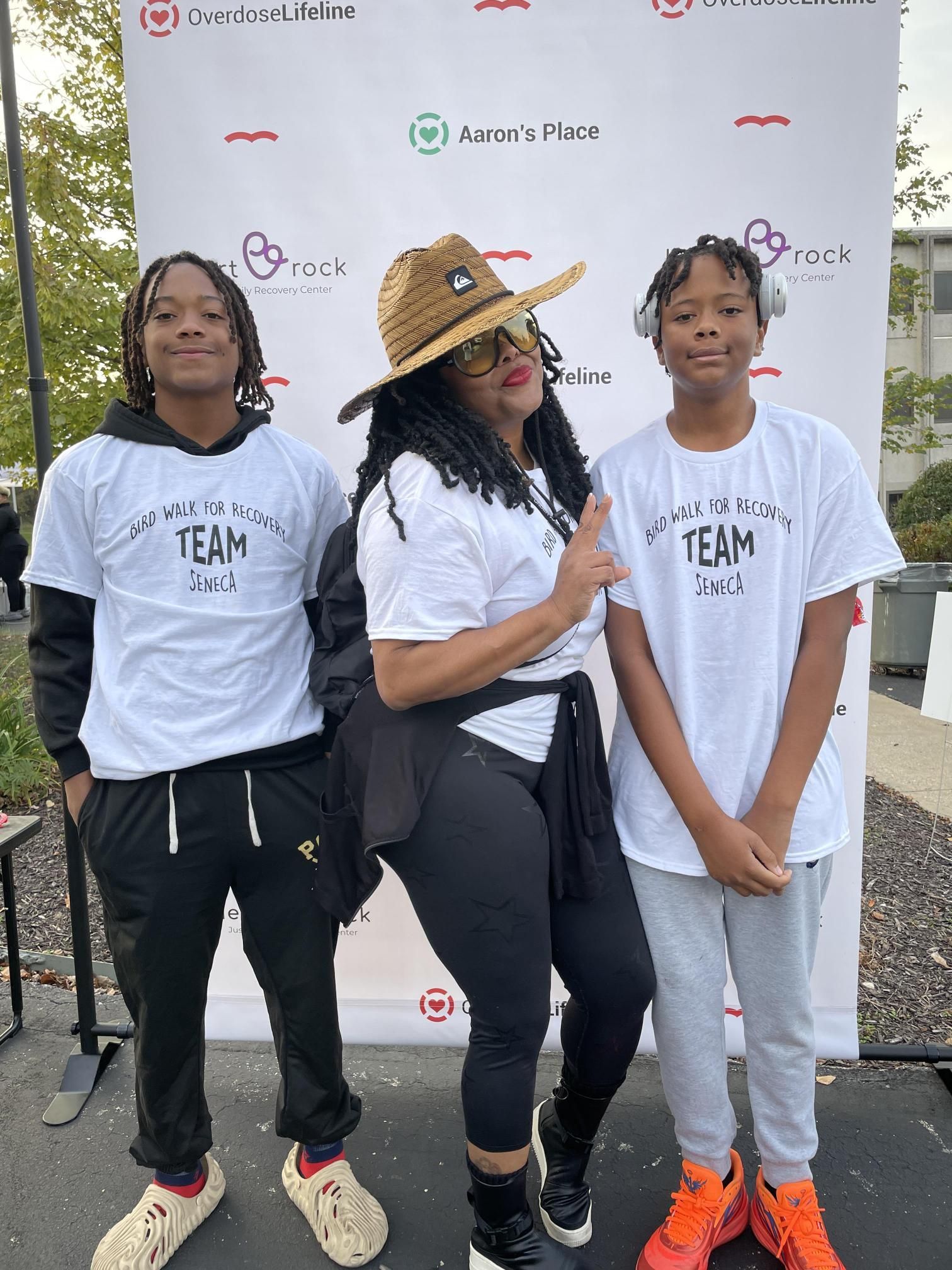A woman and two boys are posing for a picture in front of a wall.