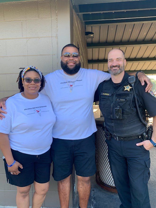 A man and two women are posing for a picture with a police officer.