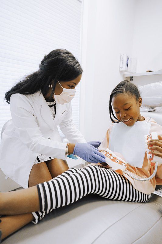 A dentist is examining a little girl 's teeth in a dental office.