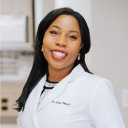 Woman in white lab coat smiles at the camera, possibly a healthcare professional.