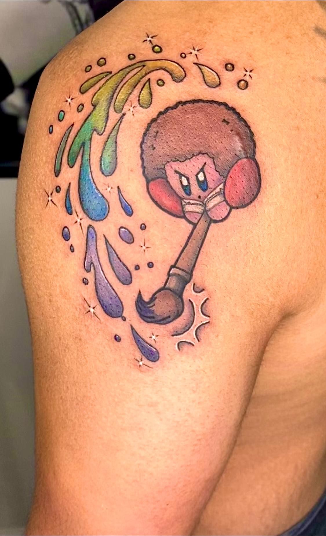 A man has a tattoo of bob ross on his shoulder.