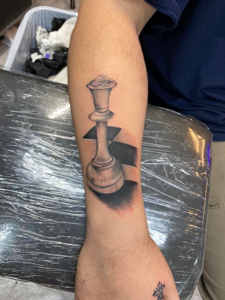 A person has a tattoo of a chess piece on their arm.