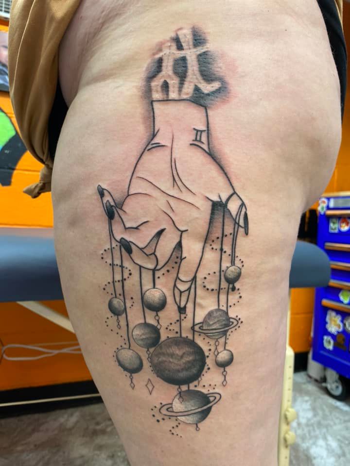 A tattoo of a hand holding planets on a woman 's leg