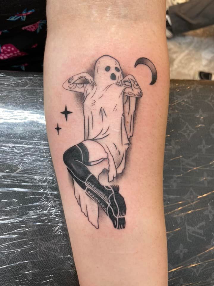 A black and white tattoo of a ghost on a person 's arm
