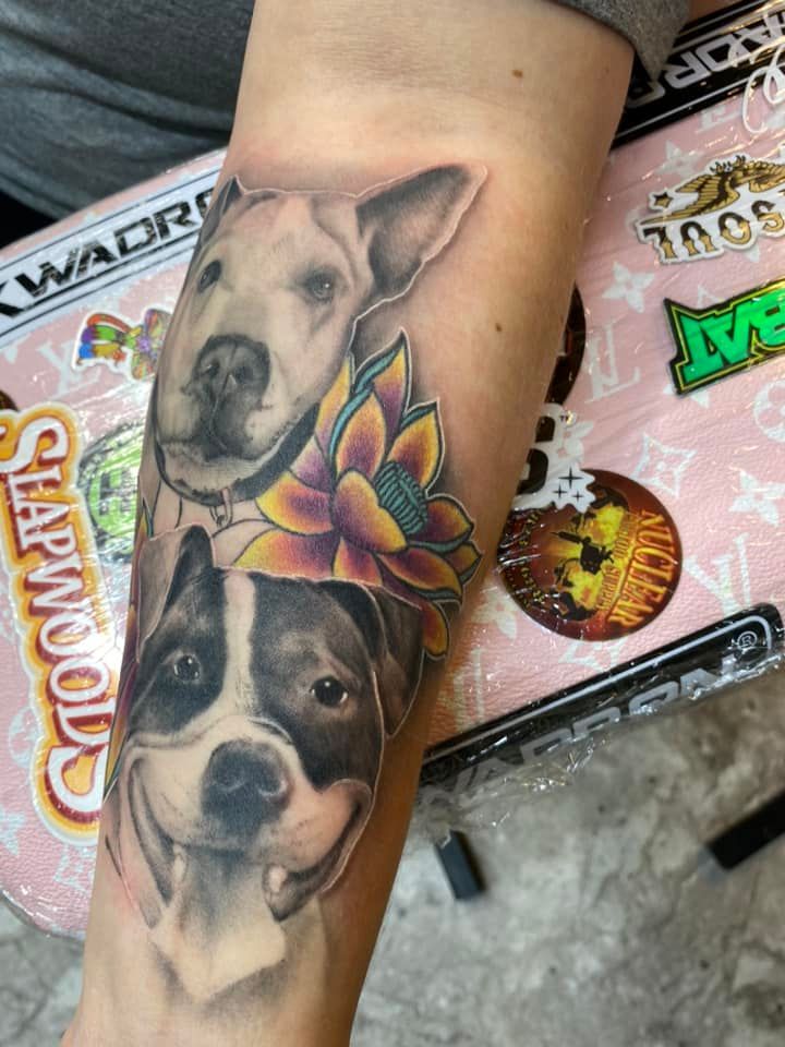 A woman has a tattoo of two dogs and a flower on her forearm.