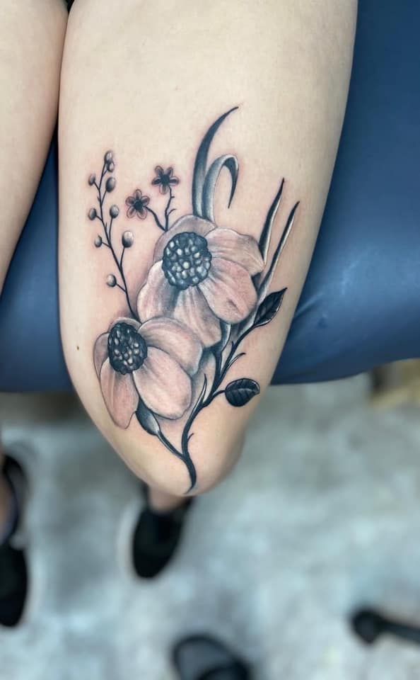 A woman has a tattoo of flowers on her leg.