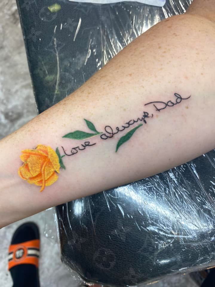 A person has a tattoo on their arm that says `` love always dad ''.