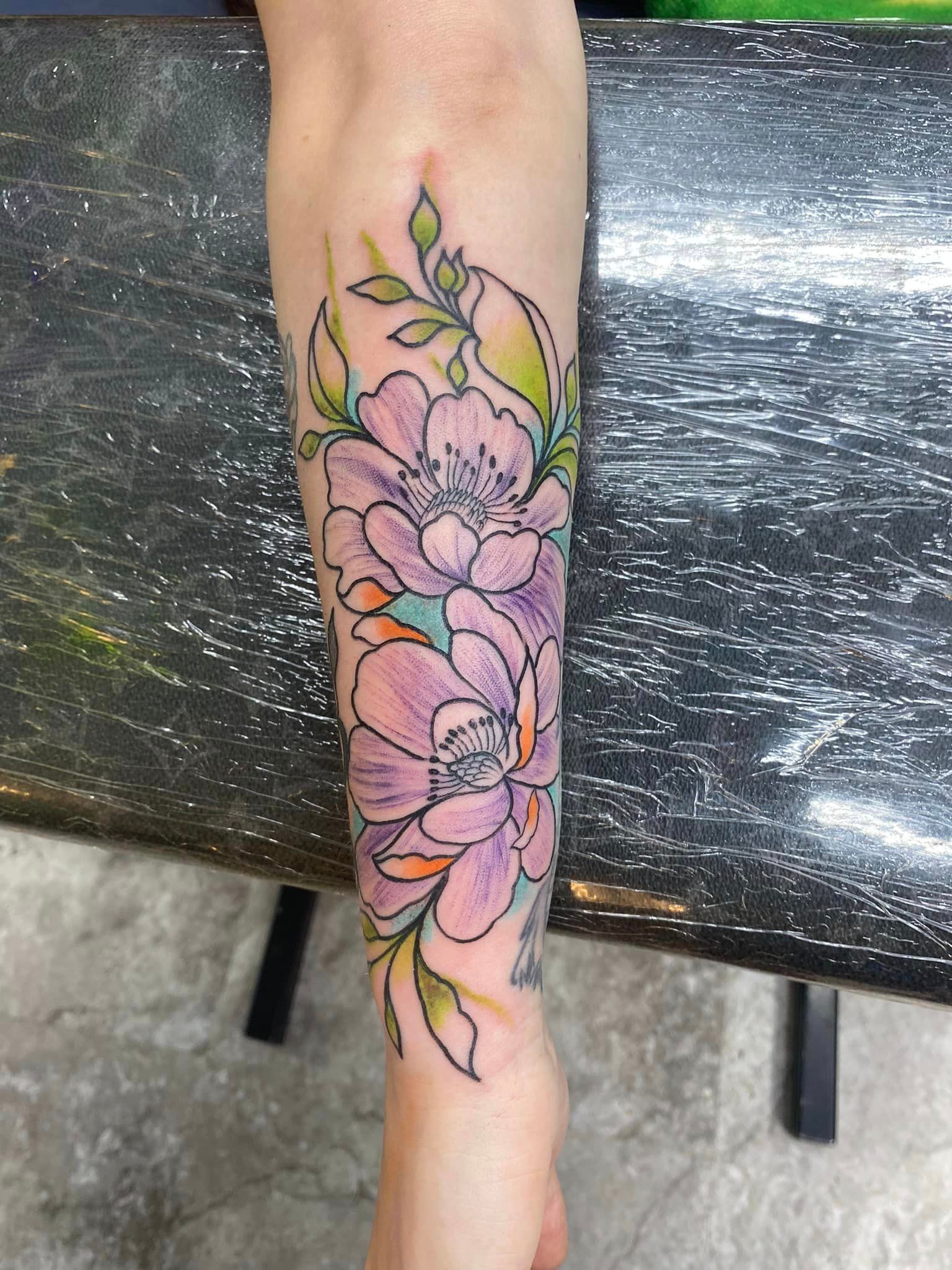 A woman has a tattoo of flowers on her forearm.