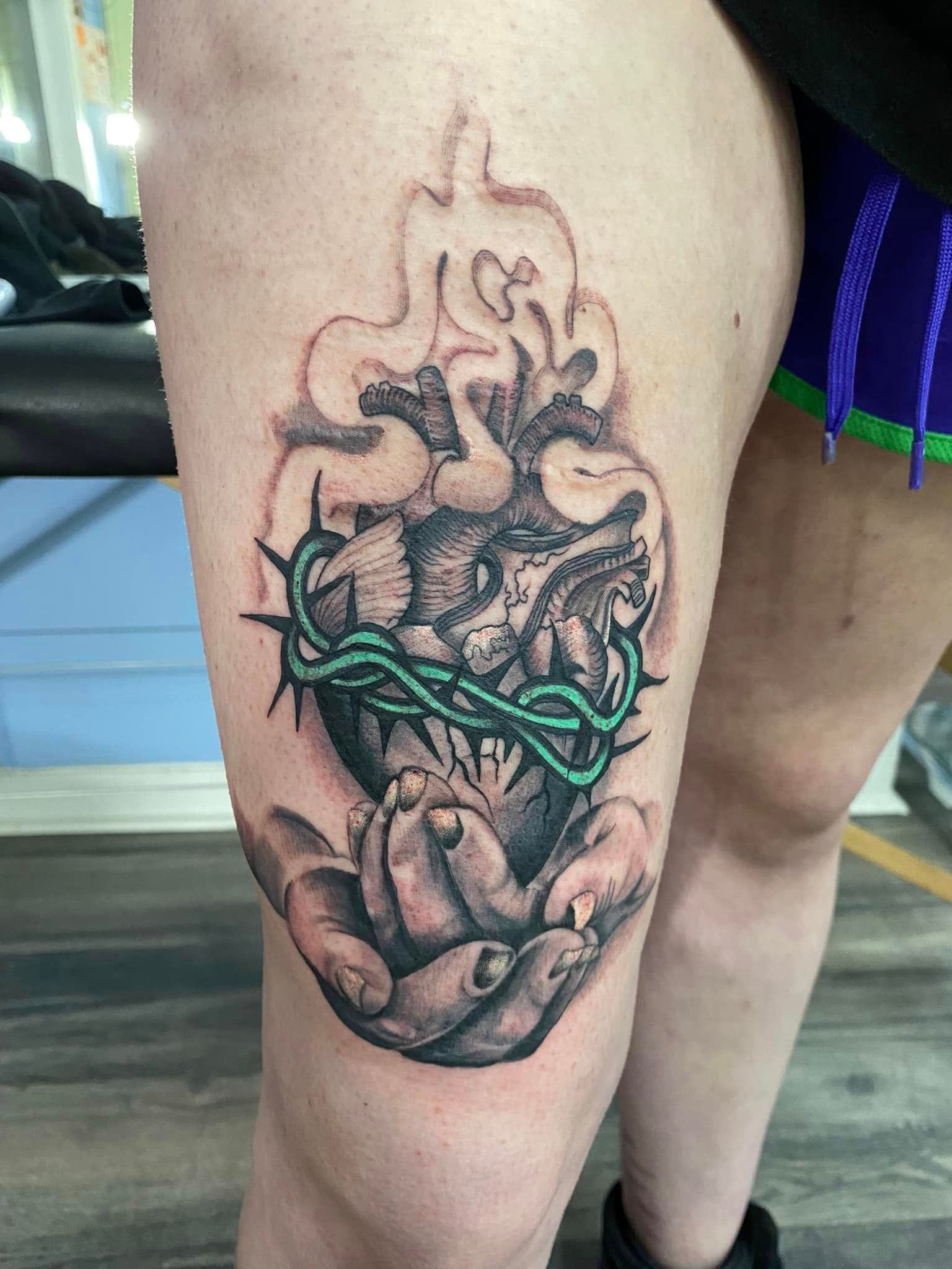 A woman has a tattoo of a heart with thorns on her thigh.