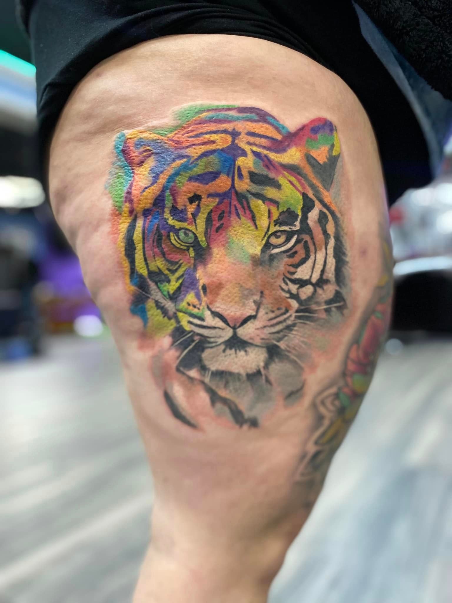 A woman has a colorful tiger tattoo on her leg.