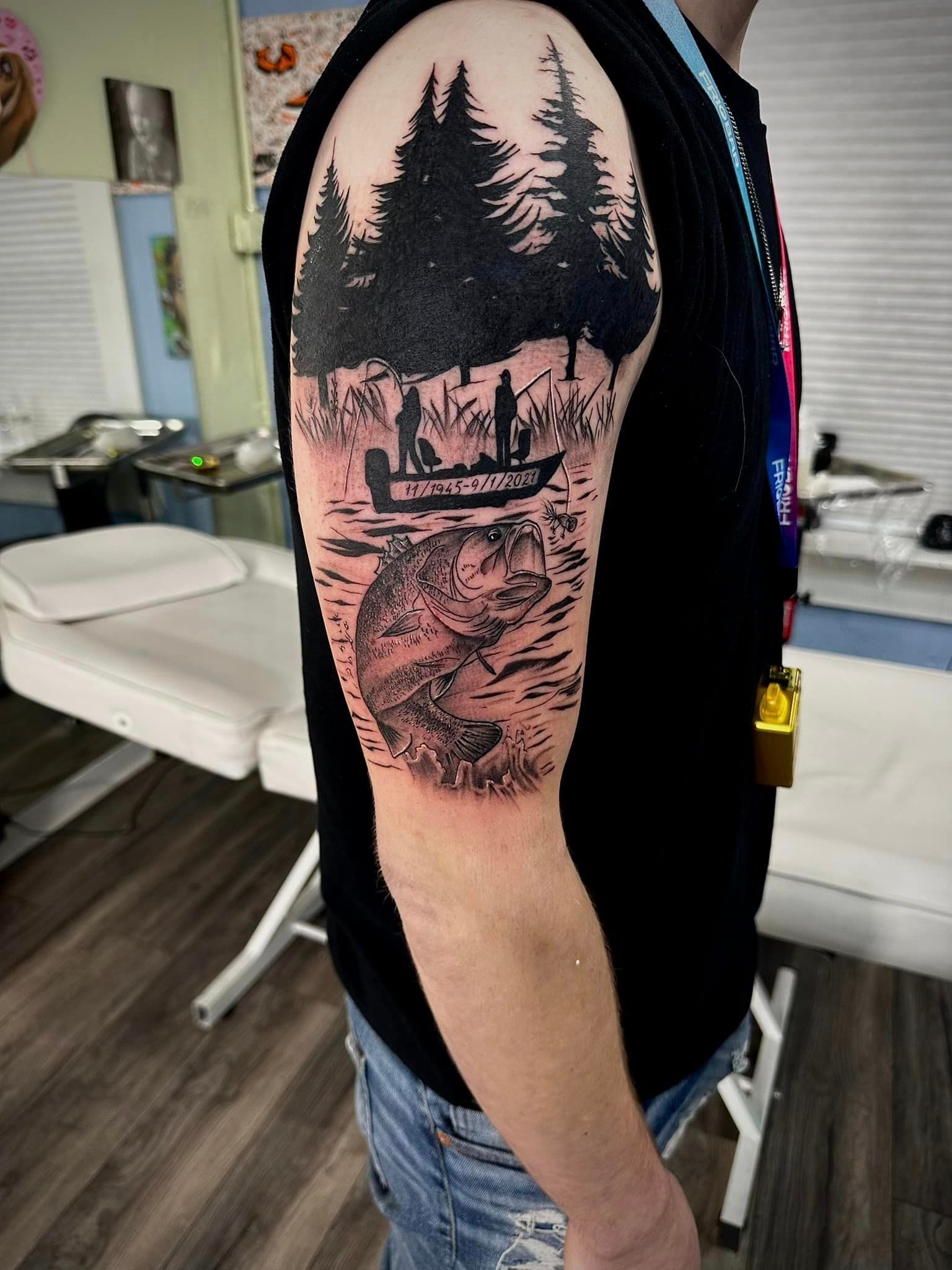 A man has a tattoo of a canoe in the woods on his arm.