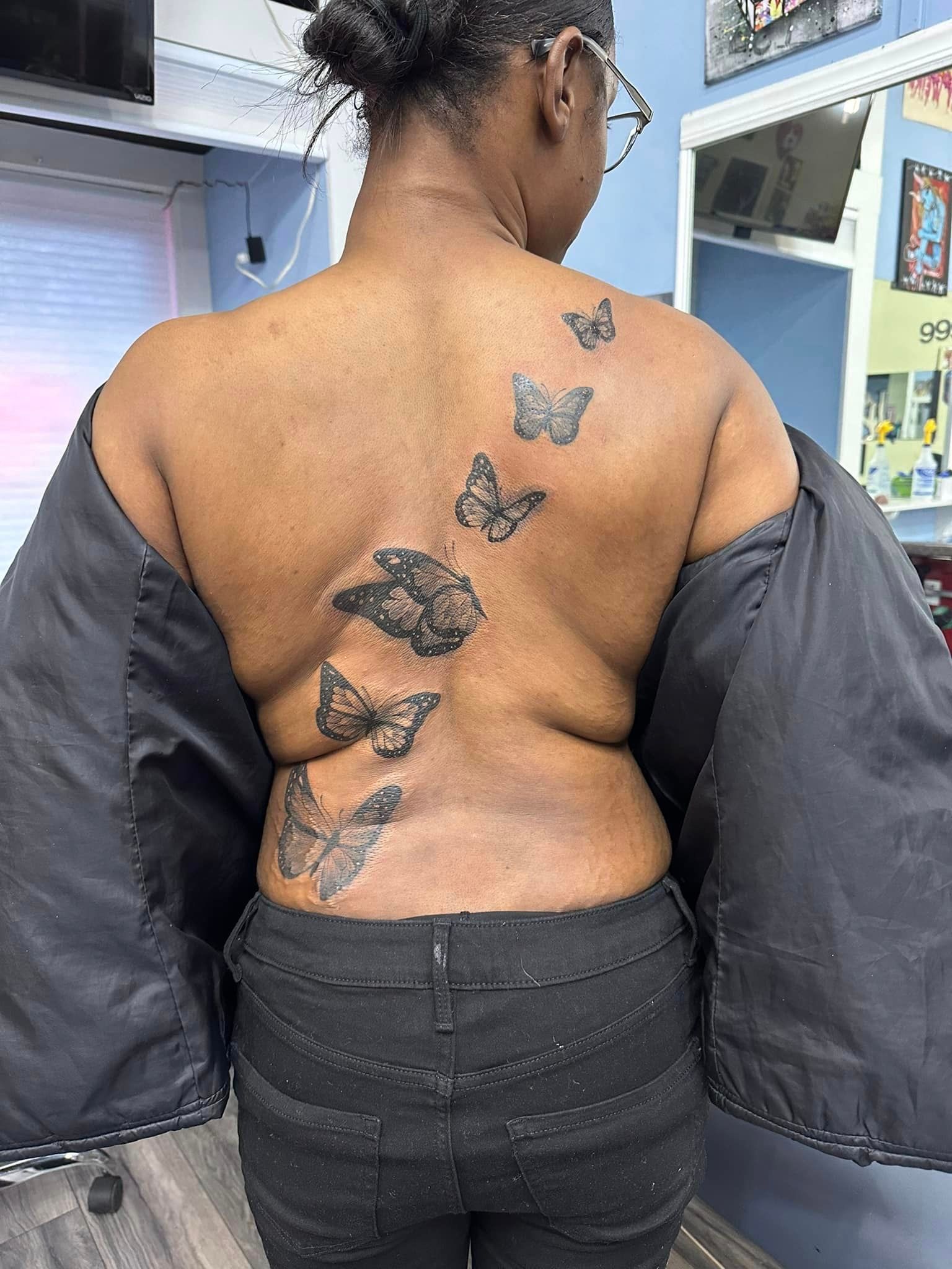 A woman has a tattoo of butterflies on her back.