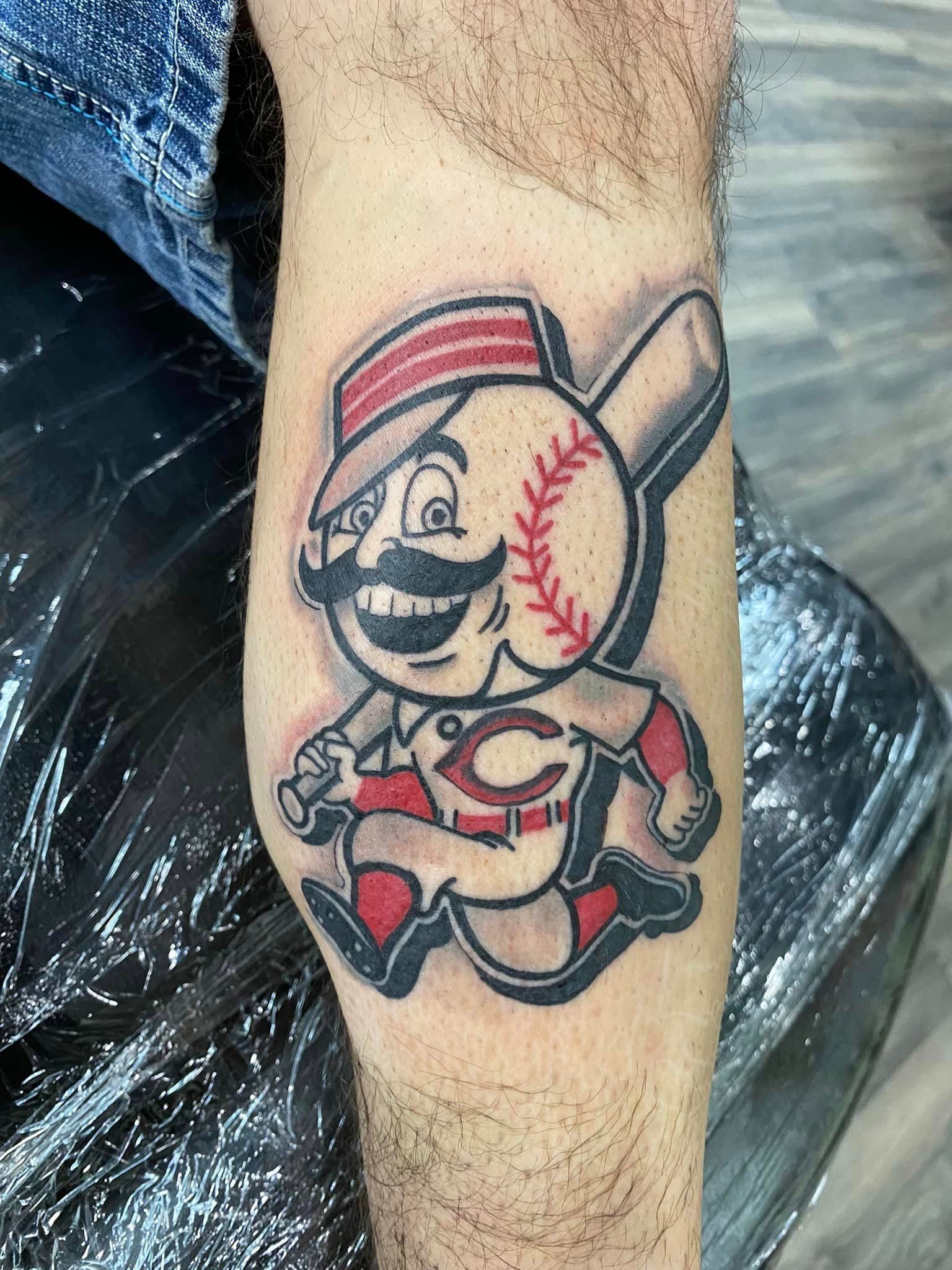 A man has a tattoo of a baseball player on his arm.