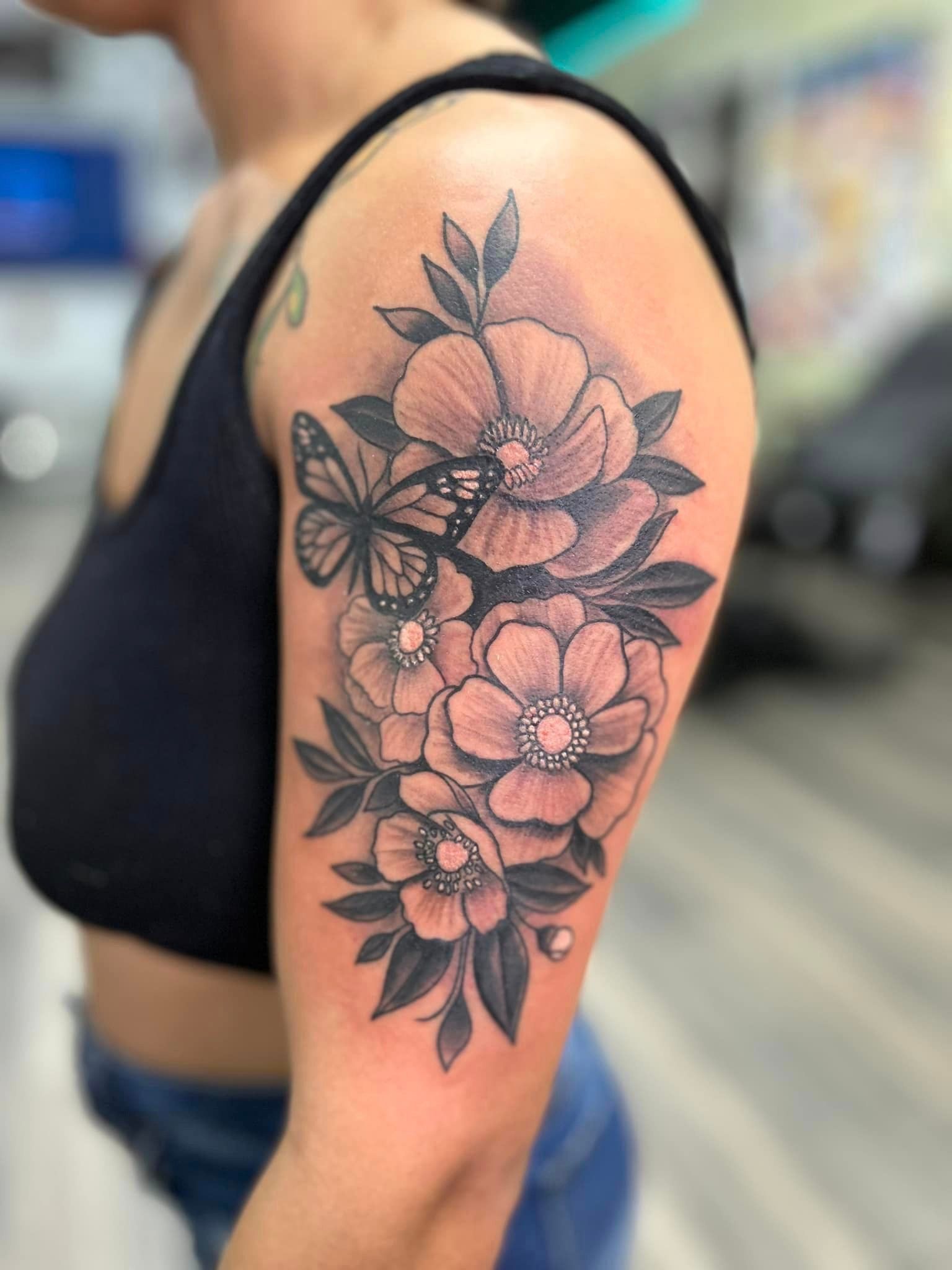 A woman has a tattoo of flowers and a butterfly on her arm