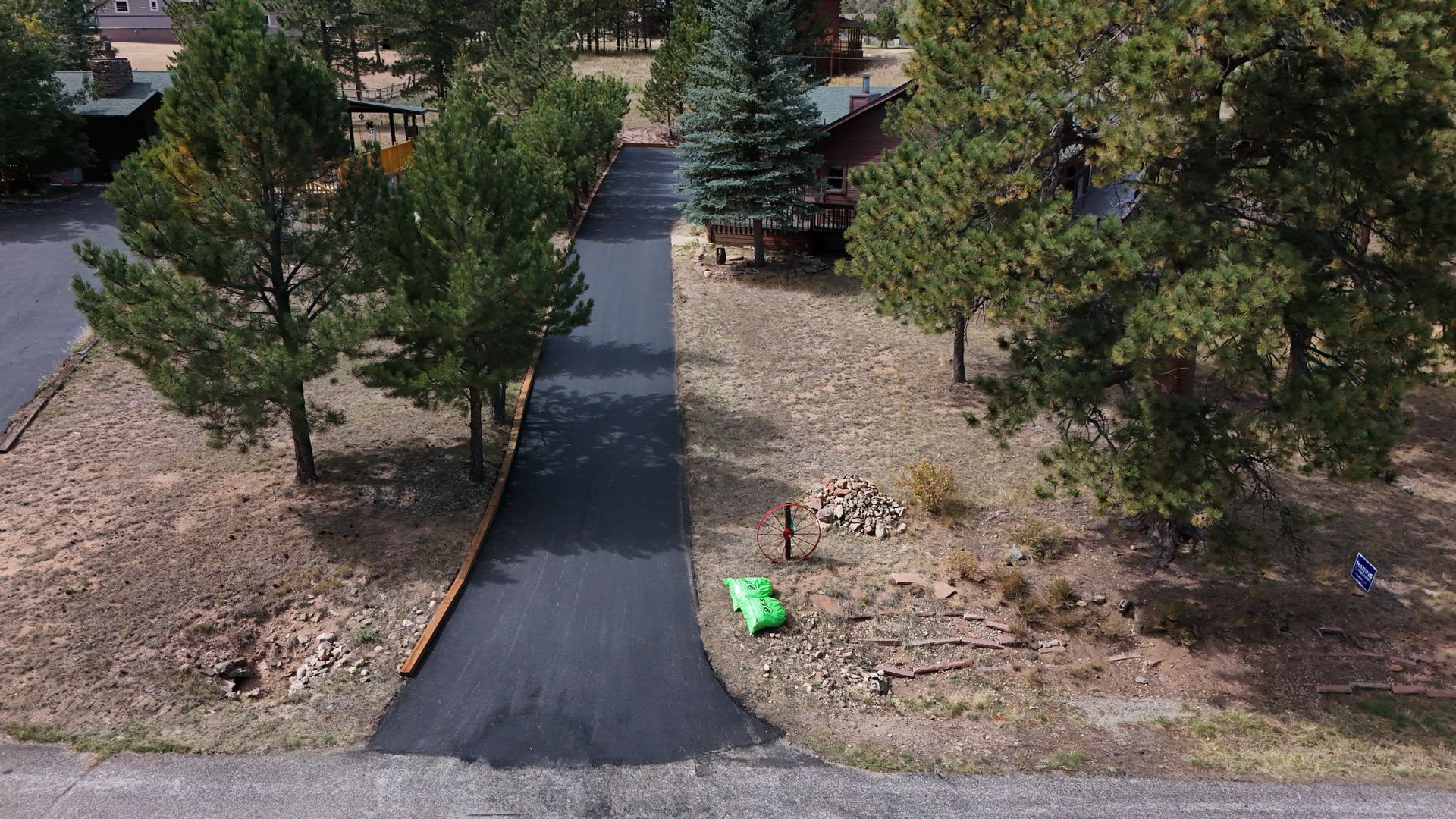 A man is driving a yellow roller on a road in front of a house.
