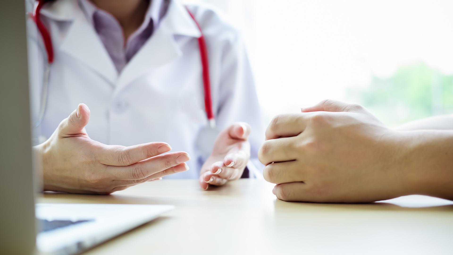 A doctor is talking to a patient while sitting at a table.