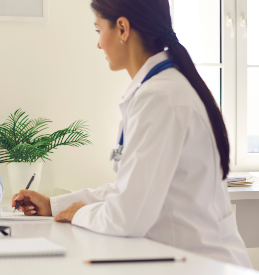 An elderly man is sitting at a table talking to a doctor.