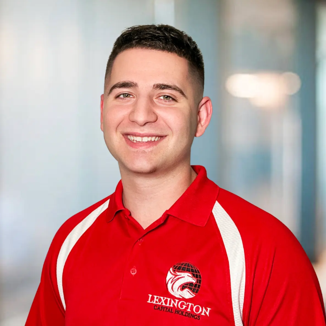 Man in red polo shirt with Lexington Clinic logo smiling at the camera. White sleeves, blurred background.