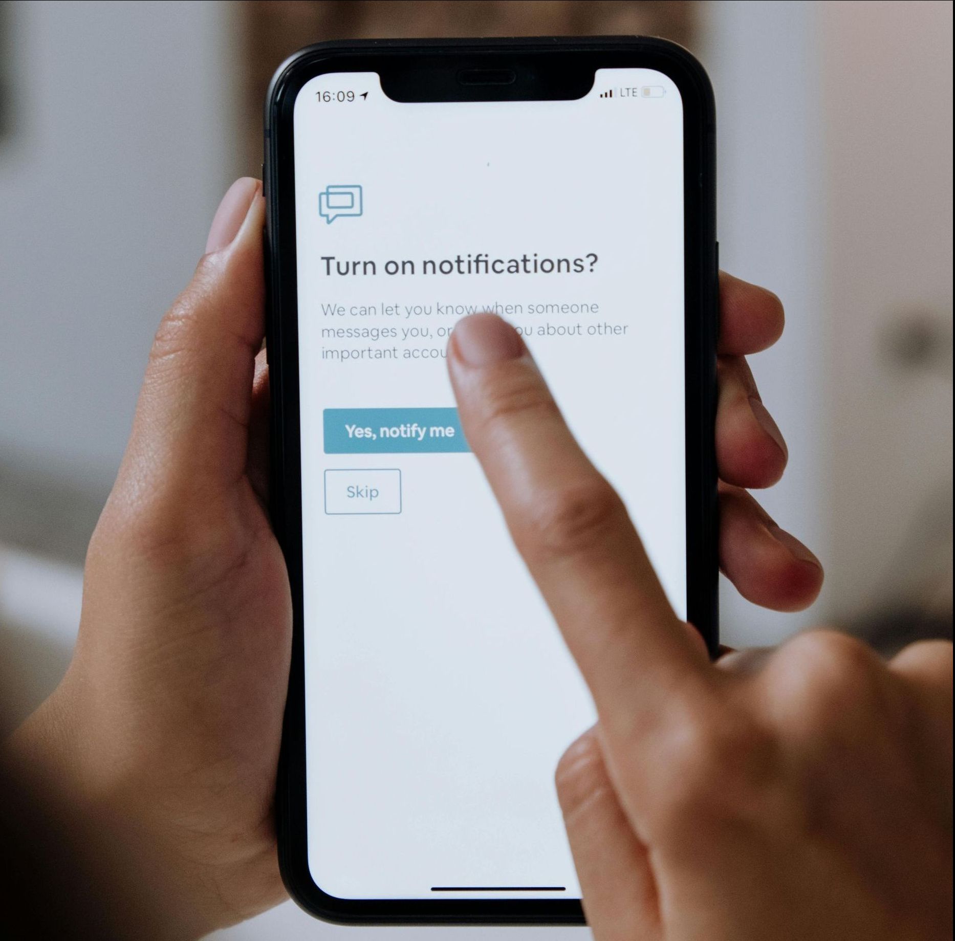Person's hand using phone, displaying a notification asking to turn on notifications.