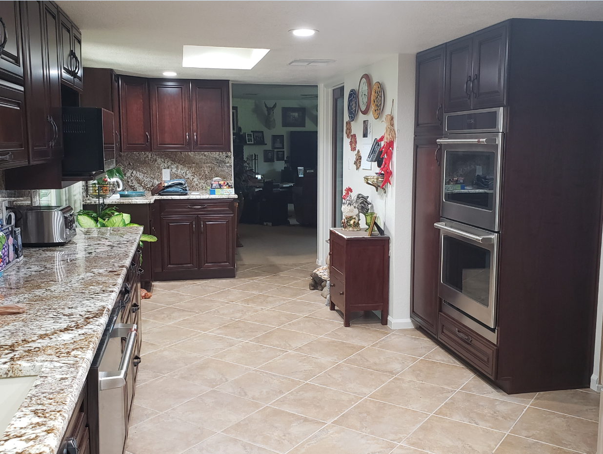 Modern kitchen with dark wood cabinets, granite countertops, and stainless steel built-in oven.