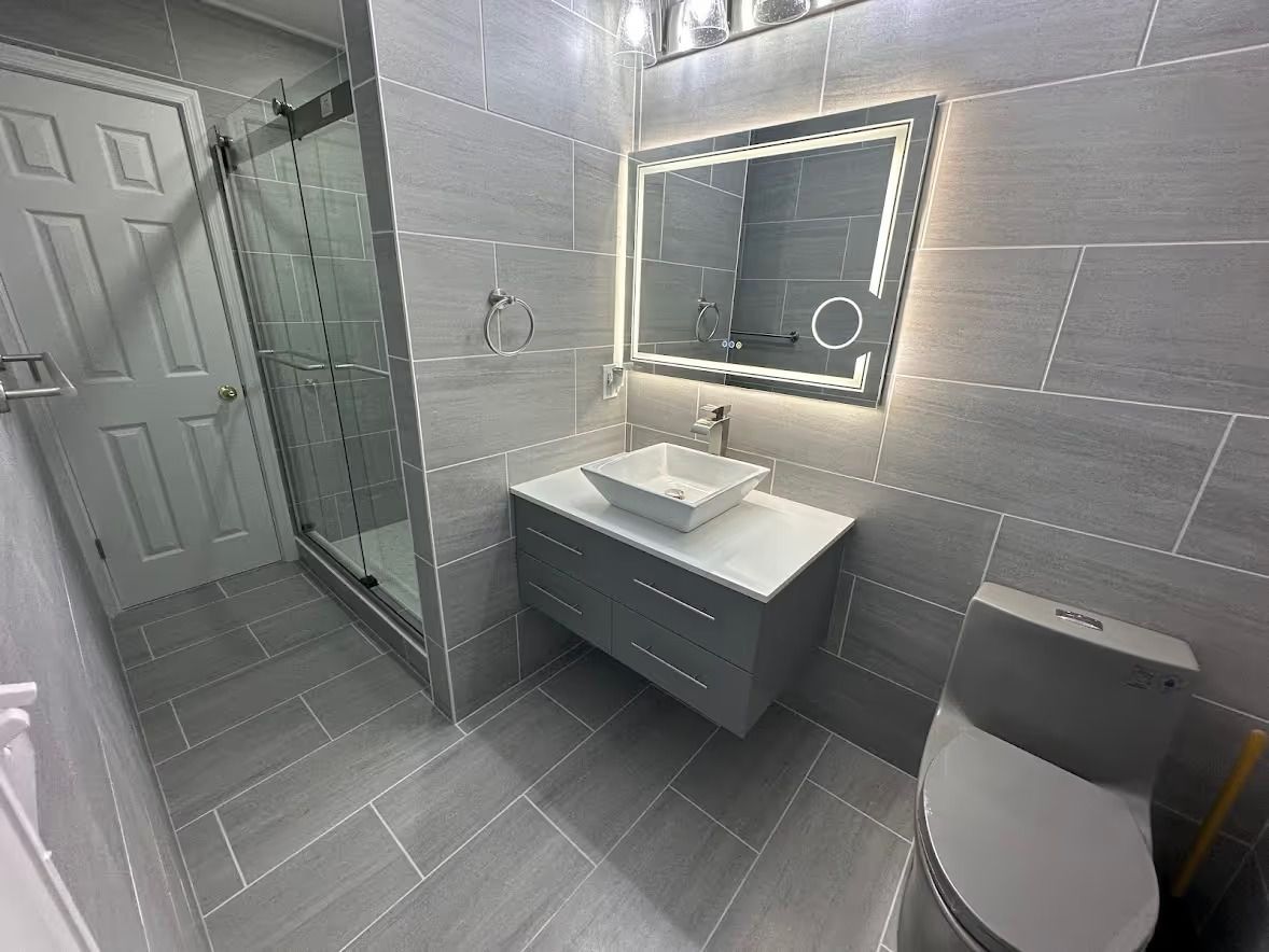 A bathroom with a sink , toilet , shower and mirror.