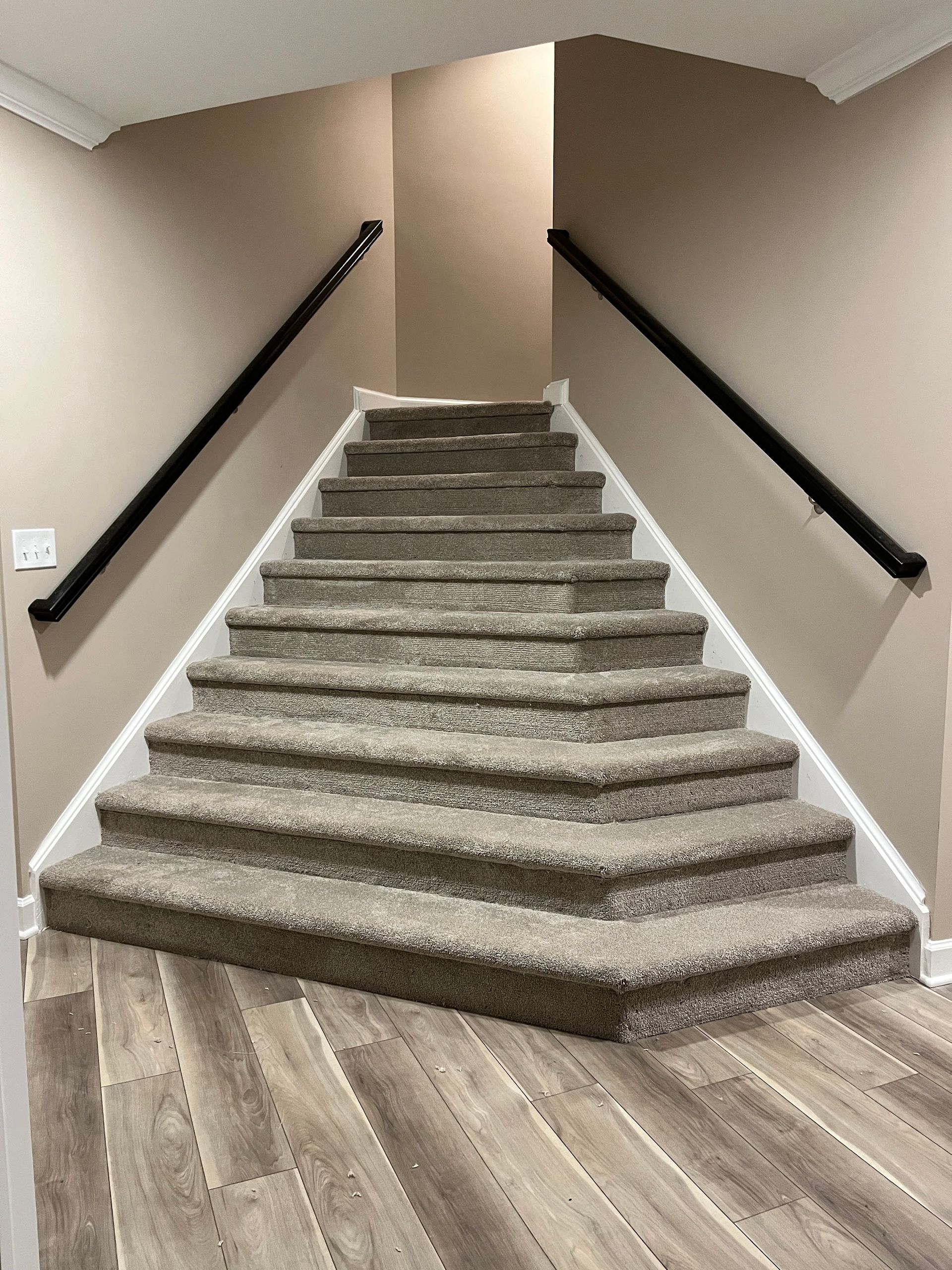 Finished basement stairs in Finksburg with espresso black railings, stair carpet, and LVT flooring