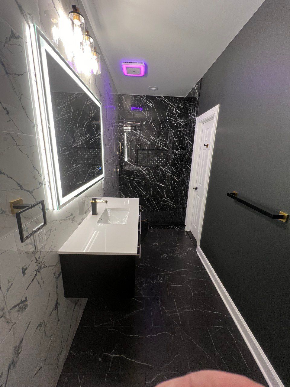 Modern master bathroom in Reisterstown with black shower, black tile floor, floating vanity, LED mirror, and Bluetooth exhaust fan