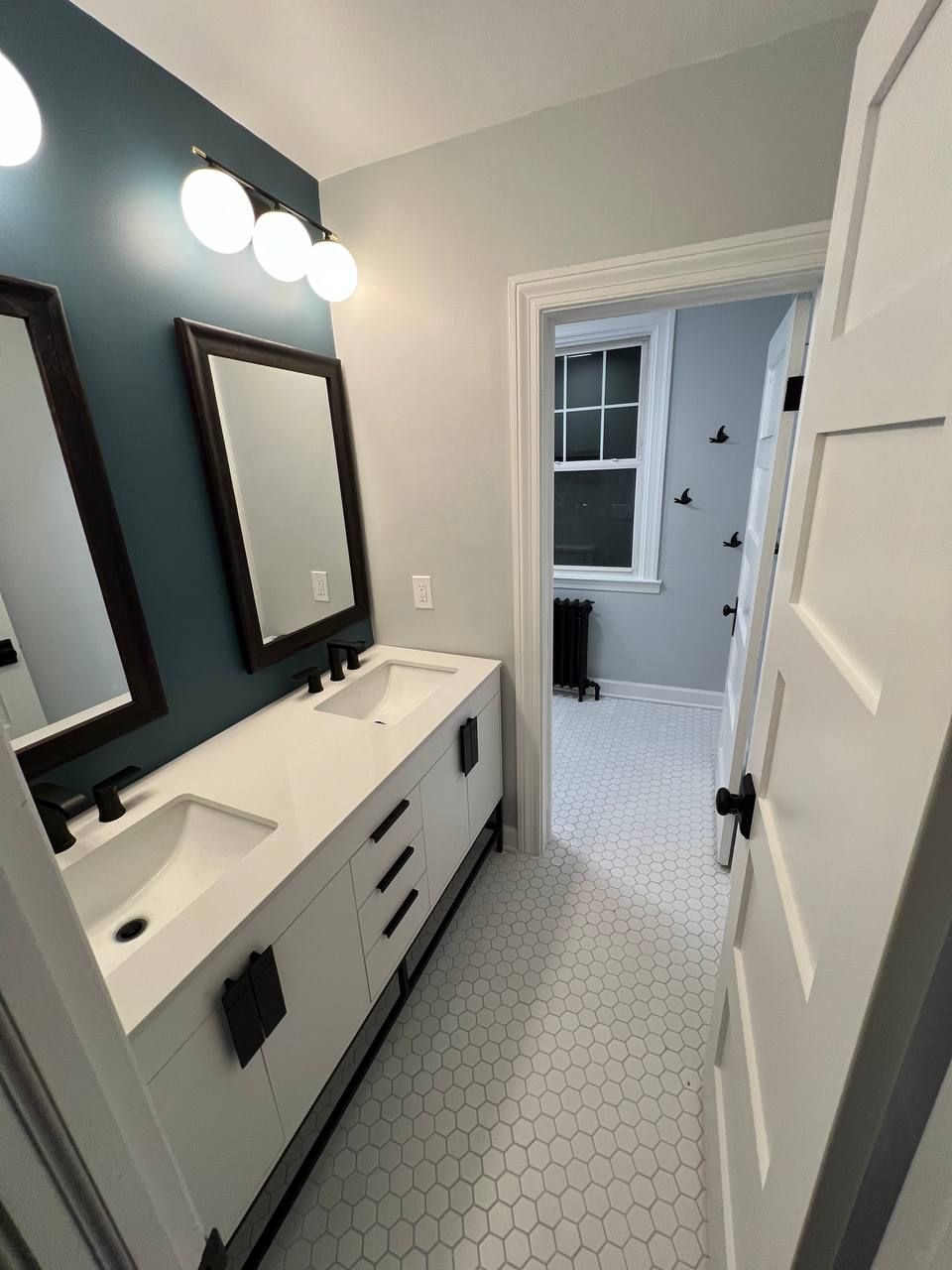 Bathroom remodel with white subway tiles, blue accent wall, double vanity, and wood-look flooring in Baltimore, MD