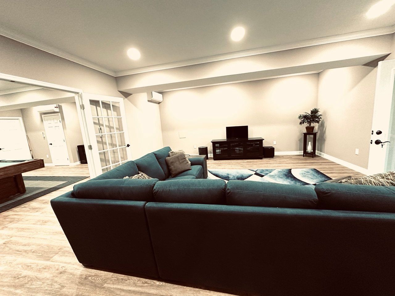Finished basement in Finksburg with LVP flooring, wood barn door, bedroom, bathroom, gym, game area, living space, crown molding, and home theater room