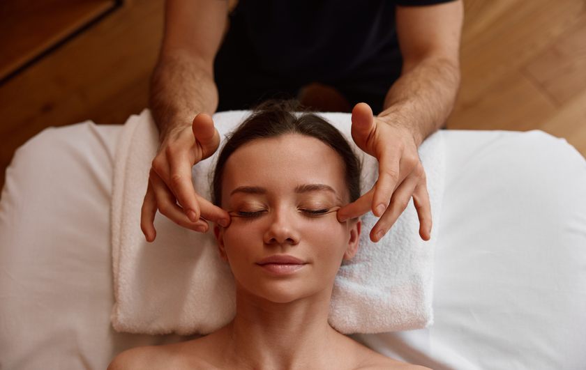 A woman is getting a head massage from a man in a spa.